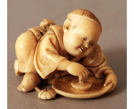 A GOOD QUALITY JAPANESE MEIJI PERIOD IVORY NETSUKE, unsigned, carved in the form of a boy leaning forward and playing with a 