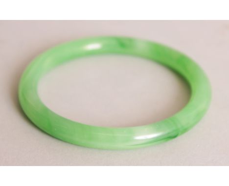 A CHINESE APPLE GREEN JADE-LIKE BANGLE, 3.1in diameter, the inner rim 2.4in diameter.