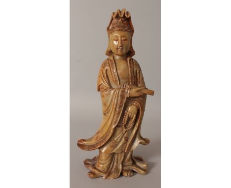 A 19TH CENTURY CHINESE CARVED SOAPSTONE FIGURE OF GUANYIN, bearing a scroll and standing in cloud engraved flowing robes, 10i