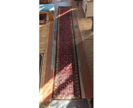 A Persian long runner, having geometric decoration on a red ground within trailing borders573 x 82cm
