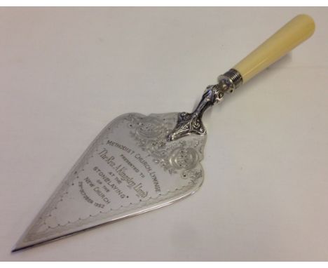 A silver plated decorative presentation trowel with silver collar. Presented to Reverand Kinglsey Lloyd at the stonelaying of