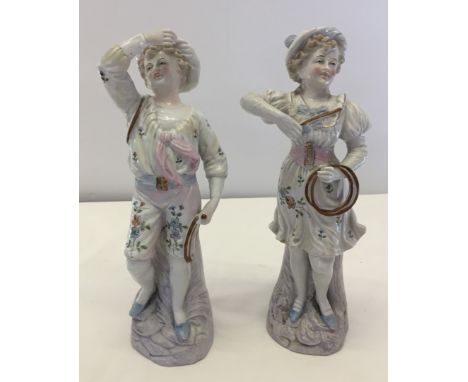 A pair of continental figurines of children playing with hoops. One figure restored. Approx height 26cm. 