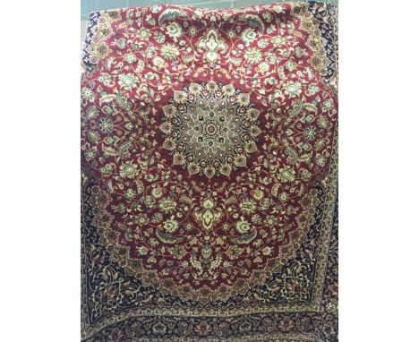 A large Keshan ground carpet of red colouration. With black brown and beige design to outside. Approx 280 x 200cm. 