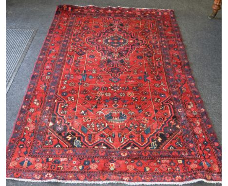 A Hamadan carpet in vibrant tones of Peacock blue, cerise and cream on a claret ground, ribbon tied medallion surrounded by f