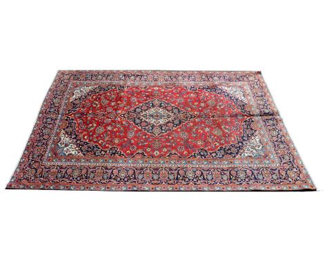 A Kashan carpet, central lozenge in tones of cream and indigo blue, conforming border, 316cm x 213cm 