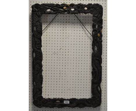 A late 19th / early 20th century Chinese ebonised picture /scroll frame, profusely carved with Dragons amongst clouds bone an