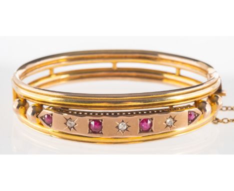 An Edwardian diamond and ruby bangle, openwork design hinged bangle, the front panel star and square set with alternating cir