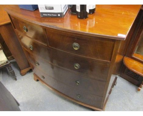 An early 20th century mahogany bow fronted chest of two short and three long drawers, having ring shaped handles and bracket 