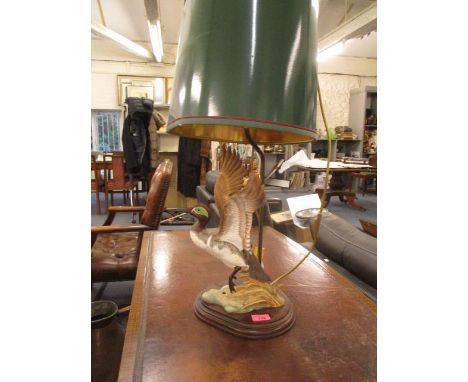 A table lamp with mahogany base and a porcelain model of a mallard in flight 