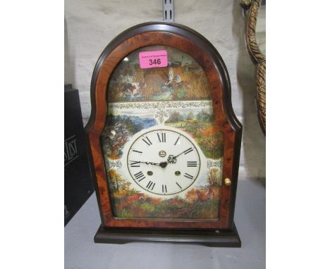 A late 20th century mantle clock, the face with Roman numerals, twin winding holes, hunting scene decoration, housed in a yew