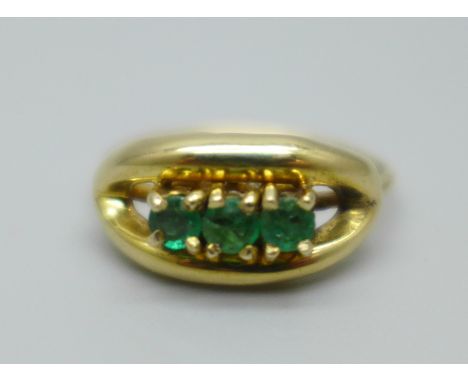 A yellow metal three stone emerald ring, marked 18ct, 2.4g, K 