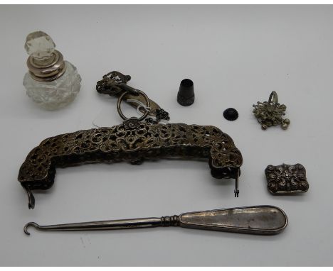 A lot comprising a white metal bag clasp, a silver part chatelaine, a button hook, scent bottle and a white metal vinaigrette