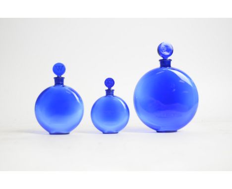 René Lalique (French, 1860-1945) a graduated set of three blue glass circular Worth perfume bottles,  the base of the bottles