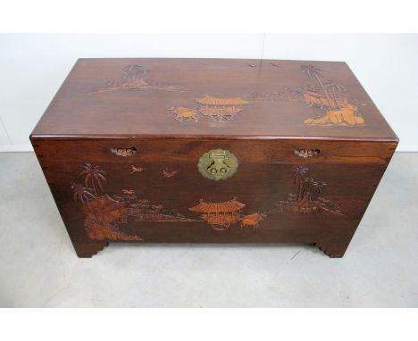 A Oriental hardwood trunk,  top and front having a moulded landscape design, inset handles to either side and makers label to