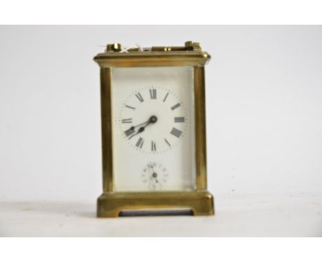 A brass carriage timepiece,  the central enamel dial with Roman numerals and lower Arabic dial, with key, height 14cm