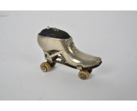 An Edwardian novelty pin cushion in the form of a roller skate,  with early rubberised wheels, length 7cm 