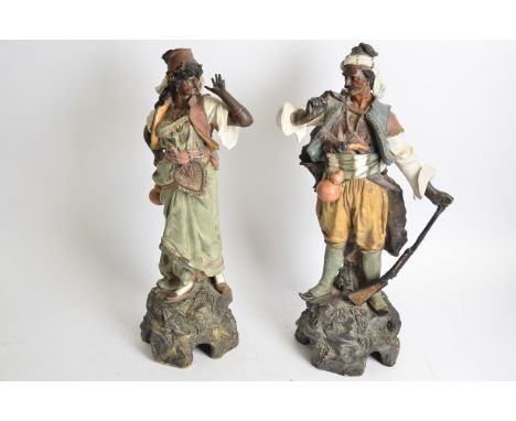 A pair of Goldscheider style painted terracotta statues of Ottoman type figures,  one female, one male, with internal impress