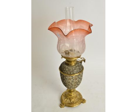A Doulton oil lamp with cranberry glass shade,  the Doulton stoneware body raised on three footed brass stand, marked "Messen