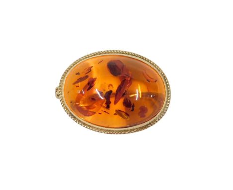 A 20thC amber brooch, the oval cabochon amber, with red brown flecks, in a rub over 9ct gold setting, Birmingham 1993, 3.4cm 