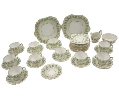 An Aynsley part tea service, on a cream ground with green three leaf clovers, comprising ten tea cups and saucers, milk jug, 