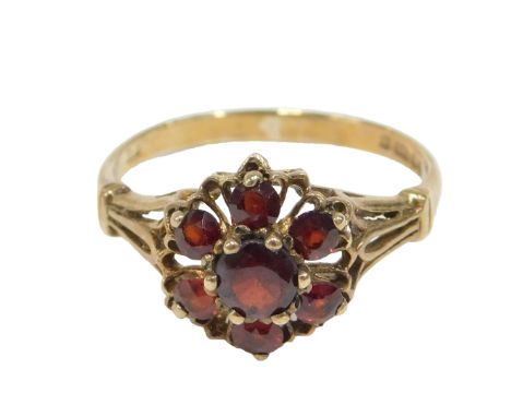 A 9ct gold garnet cluster ring, the central round brilliant cut stone, claw set, surrounded by six smaller garnets each in ye