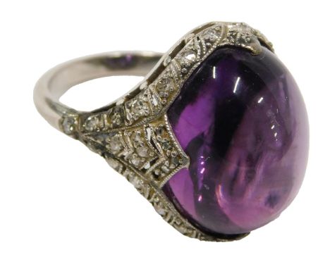 A cabochon set dress ring, set with purple cabochon stone, surrounded by white stones, in a white metal setting, unmarked, be