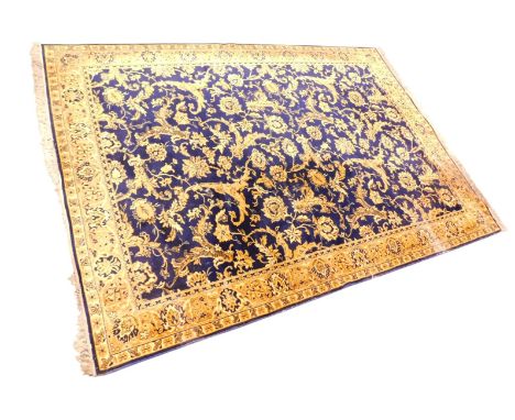 A large machine woven carpet, decorated with flowers, leaves, etc., in gold on a blue ground, one wide, two narrow borders, 3