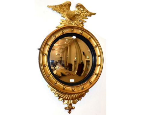 A Regency Style Gilt and Gesso Convex Mirror, late 19th century, with ebonised slip and ball surmounted frame surmounted by a