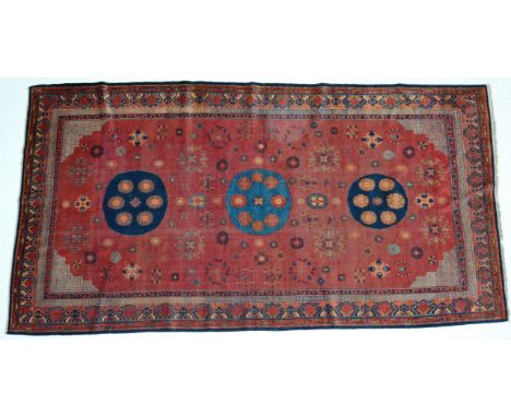 Khotan Carpet  East Turkestan, circa 1900 The terracotta field sparsely decorated with flowerheads and three roundels framed 