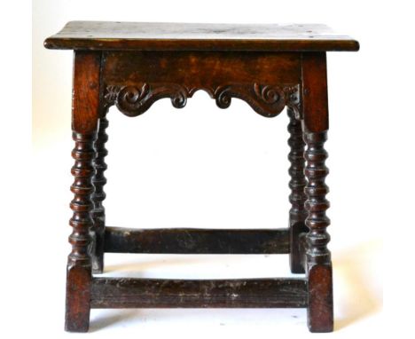 An English Joined Oak Stool, circa 1650, the six-pegged rectangular top above an S shaped scrolled frieze, raised on bobbin t