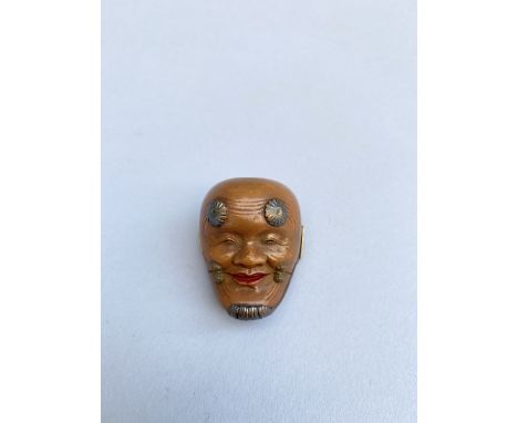 JAPON - XIXe siècle Netsuke en bois laqué, en forme de masque de théâtre de Nô, incrusté de nacre et doré. Marque au dos. Ver