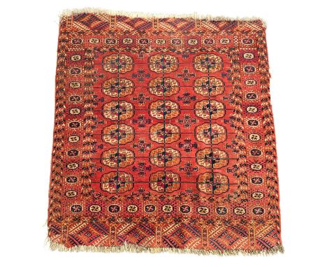 A Persian hand knotted Tekke Turkoman rug with repeated guls on a red ground, 106 by 113cms.