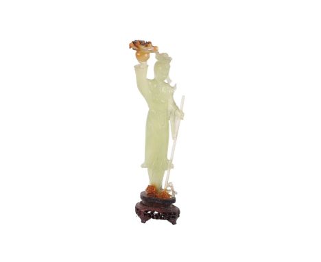 A Chinese jade / hardstone figured green figure depicting a robed woman holding a staff and a basket of flowers, 24cms high.