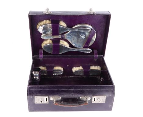 A George V leather travelling vanity case with fitted interior, the purple leather case fitted with mirror, hand brushes and 