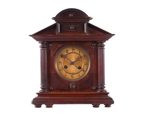 An Edwardian carved walnut architectural mantel clock fitted with an 8-day movement striking on a gong, 33cms wide.