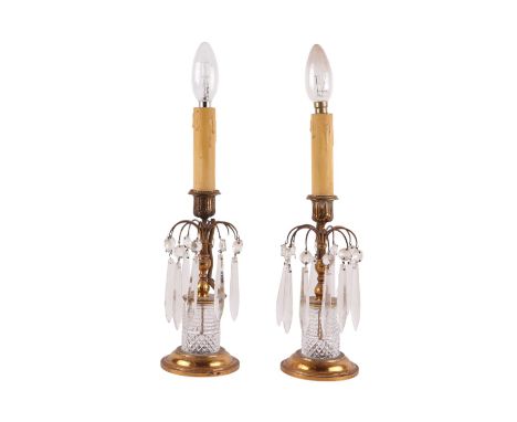 A pair of gilt metal and cut glass table lamps with prismatic drops, 35cms high overall. Provenance: property of the late act
