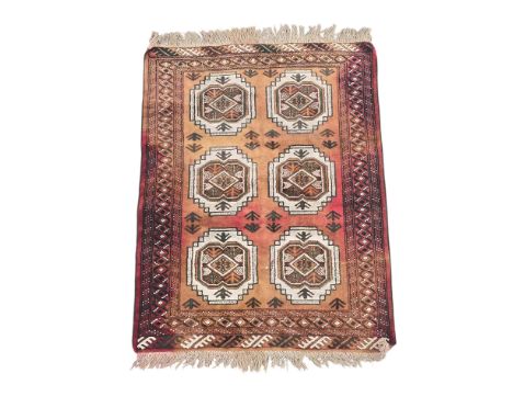 A Persian Turkoman woollen hand knotted rug with two rows of repeated medallions on a red ground, 100 by 130cms.