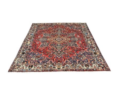 A Persian Shiraz hand knotted woollen carpet with central floral design on a red and cream ground, 400 by 330cms.