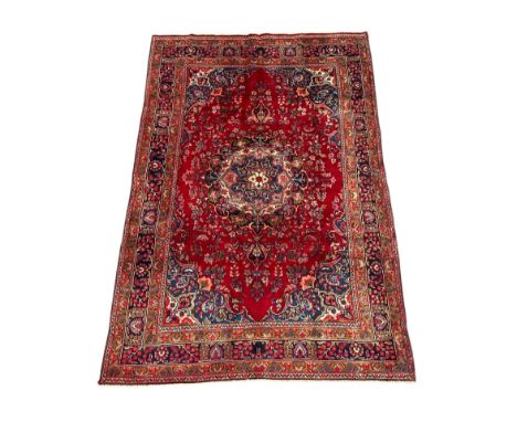 A Persian Meshed woollen hand knotted rug with central floral medallion within floral borders, on a red ground, 195 by 285cms
