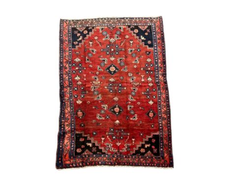 A Persian Hamedan woollen hand knotted rug with geometric design and figures, on a red ground, 143 by 200cms.Condition Report