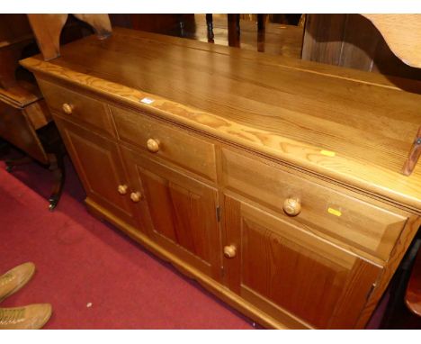 A contemporary Ercol pine dresser base having three drawers over conforming recessed panelled cupboard doors, width 134cm
