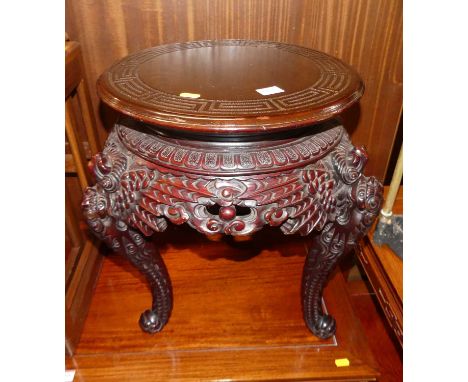 A Chinese stained and carved wood circular low urn stand, having a Greek key outer motif, raised on heavy floral scroll and p