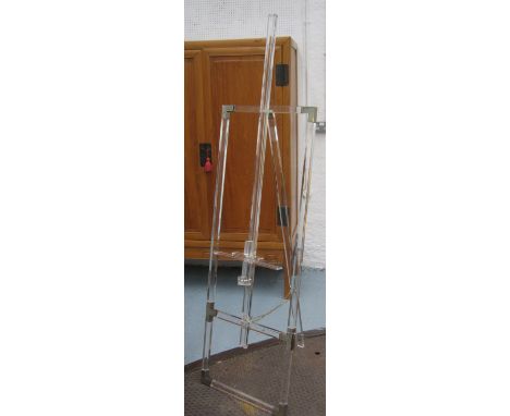 EASEL, lucite, adjustable, raised upon hinged tripod supports. 