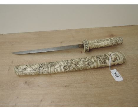A Japanese Dagger with highly carved bone hilt and scabbard depicting Samurai Warriors, blade length 25cm, overall length 38c