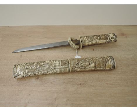 A Japanese Dagger with highly carved bone hilt and scabbard depicting Village People &amp; Houses, blade length 21cm, overall