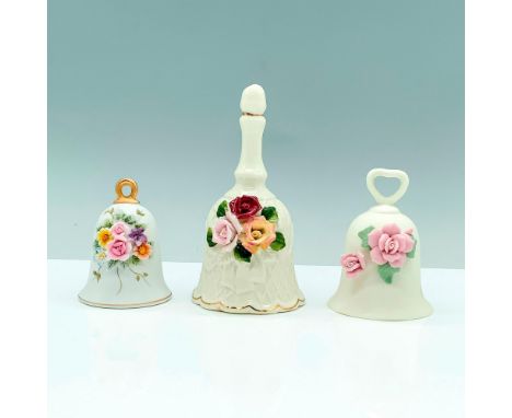A set of three white dinner bells, two matte, one glazed decorated with beautiful ceramic flowers on the center of the design