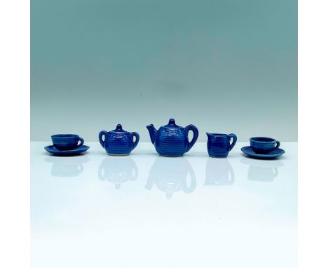 A tiny tea set that is painted a deep blue with linear textures consisting of 1 teapot, 1 sugar jar, 1 creamer, 2 teacups, an