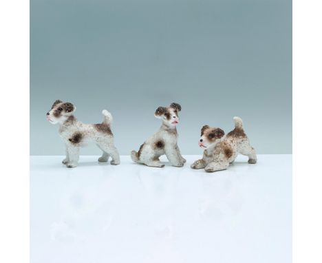 A set of three white and ash-colored figurines of wire fox terriers in three different poses, standing, sitting, and in a pla