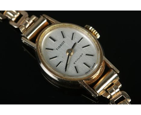 A ladies 9ct Gold Tissot stylist manual writstwatch, on rolled gold bracelet strap. Features baton markers to a silvered dial