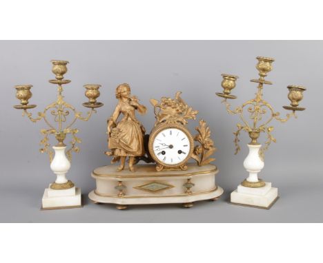 An antique French gilt bronze figural mantel clock garniture, with two bronze candelabra. The clock features an alabaster bas